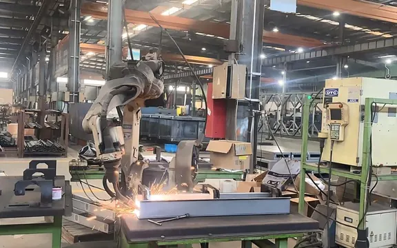 Robotic welding arm welding a diesel generator base frame and fuel tank at H&C manufacturing facility