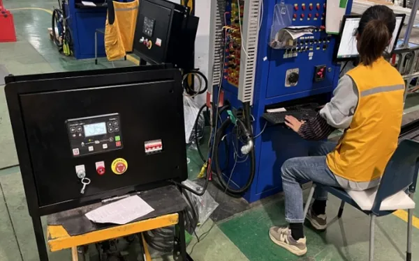 Operator testing a finished diesel generator control cabinet on the instrumented test bench at H&C factory