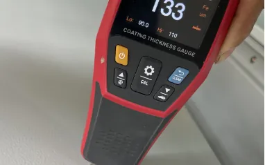 Coating thickness gauge measuring powder coat thickness on a diesel generator canopy at H&C factory